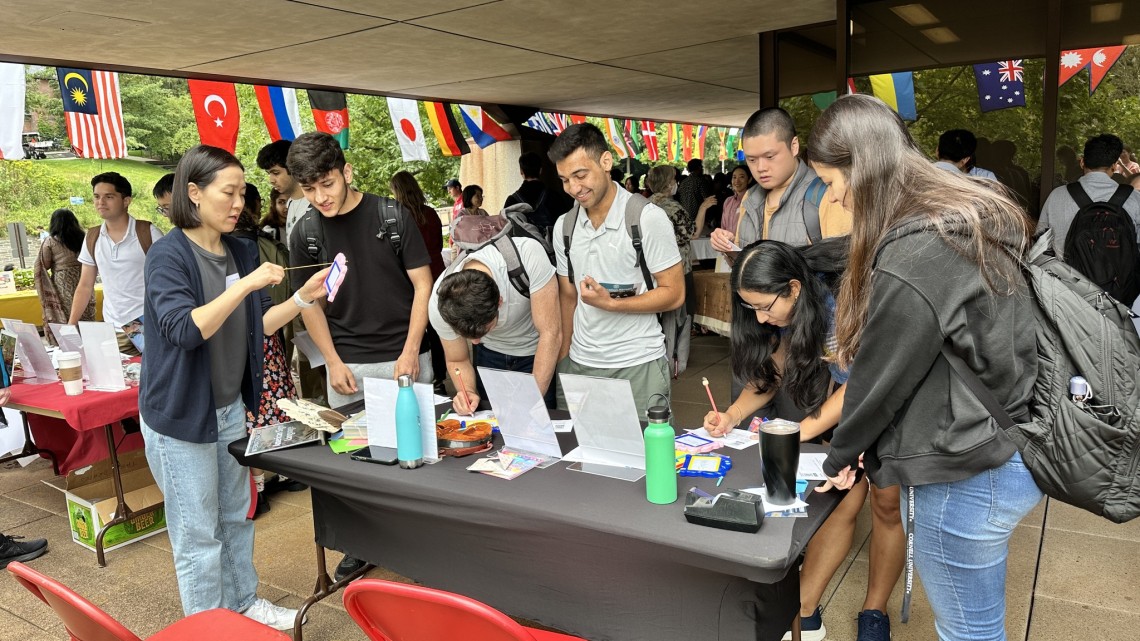 Students gather around a table at International Fair. 