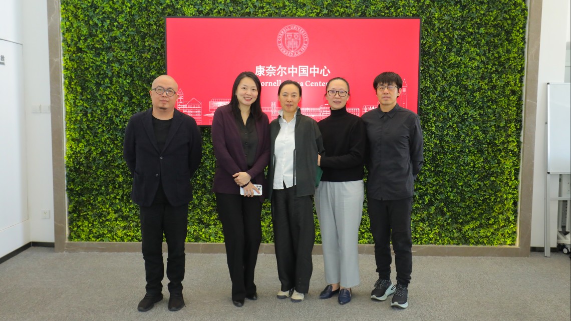 Panelists stand in front of a Cornell China Center sign in Beijing. 