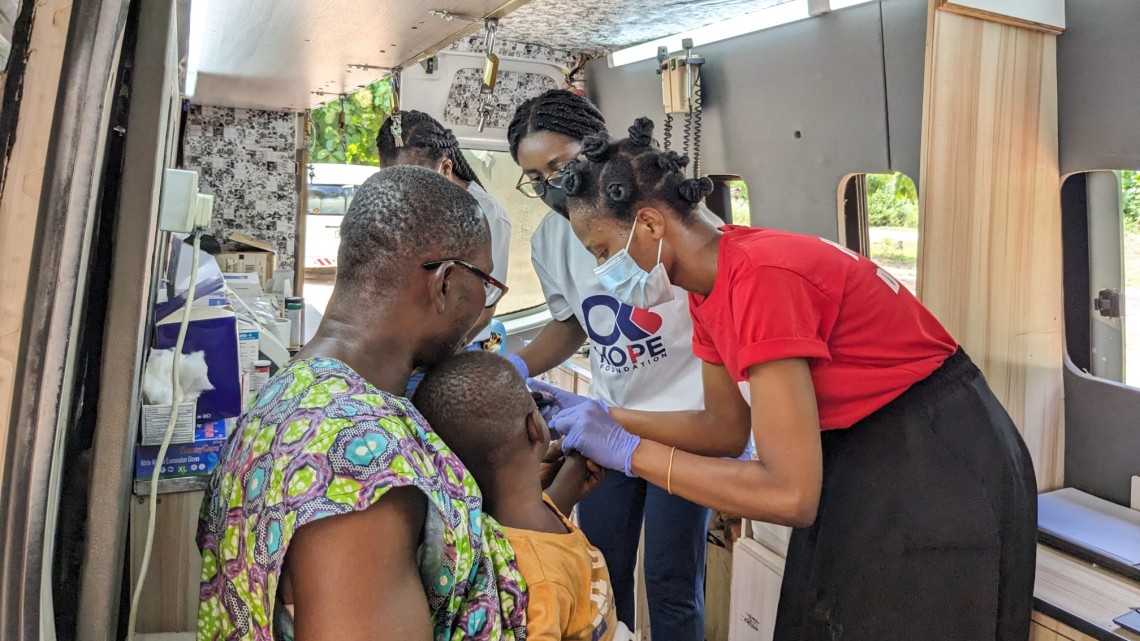 doctor giving a shot to a child inside a mobile health clinic vehicle