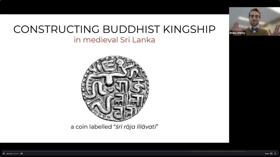 Bruno Shirley presents his winning Three Minute Thesis with PowerPoint slide reading, "Constructing Buddhist Kingship in medieval Sri Lanka" with an image of a coin and caption, "a coin labelled 'sri raja lilavati'."