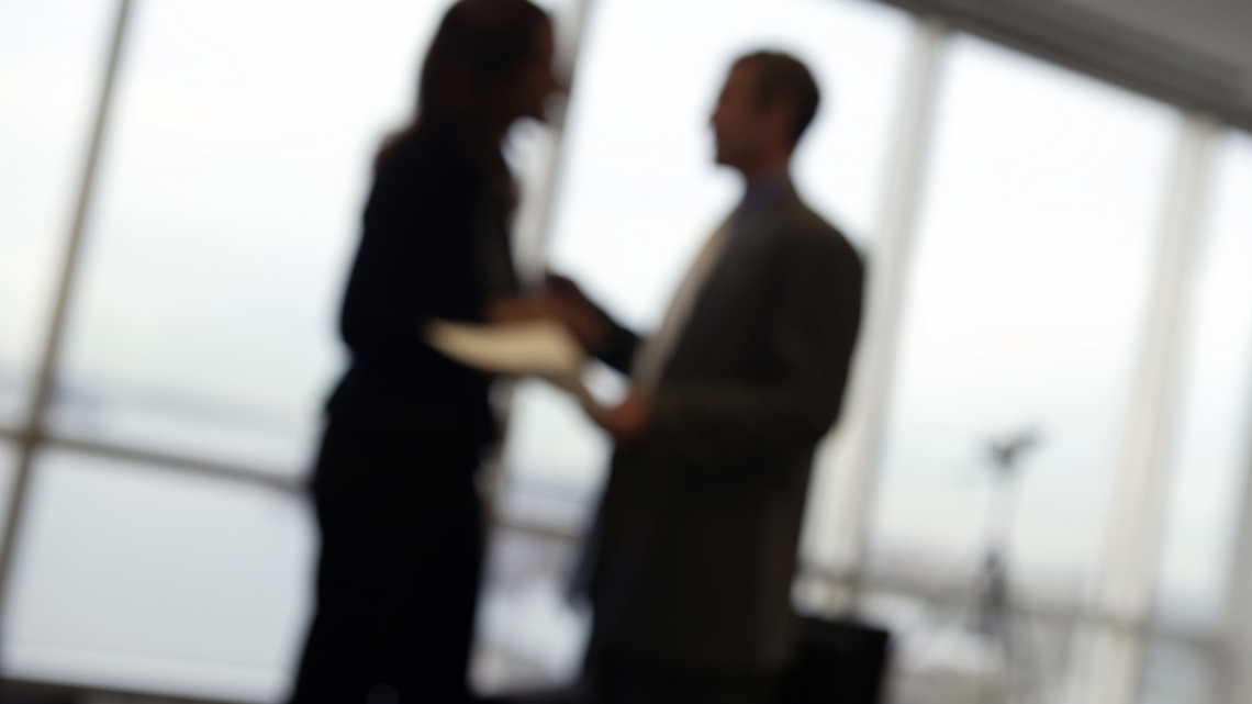 blurry silhouettes of two people talking in an office setting