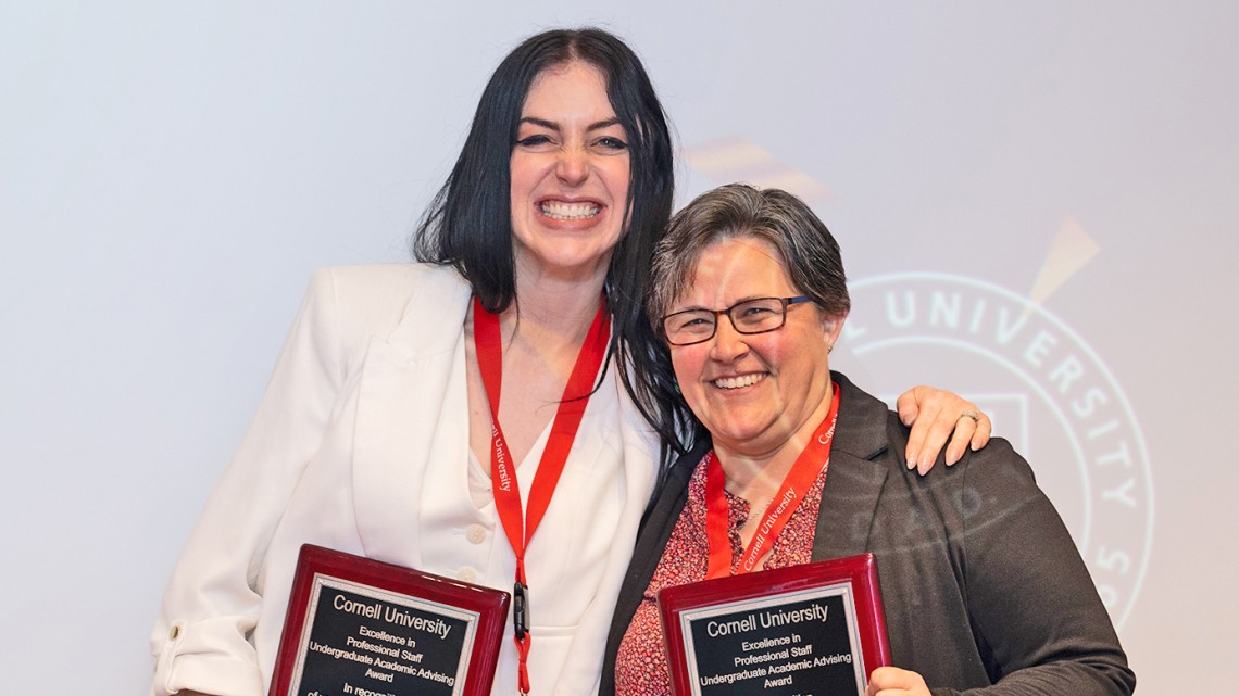 two women smiling holding awards