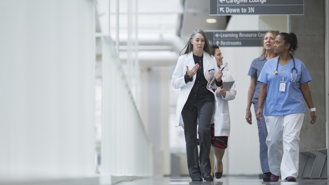 Hospital staff walk down a hallway at a hospital while talking