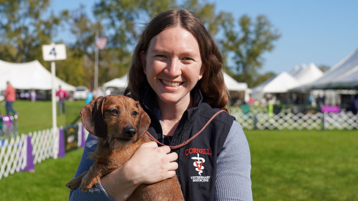 Veterinary student Michelle Greenfield on the dog show field holding a small brown dog.