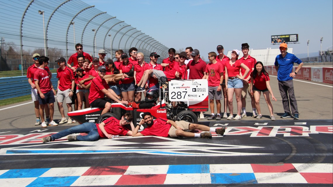 two dozen students pose on race track