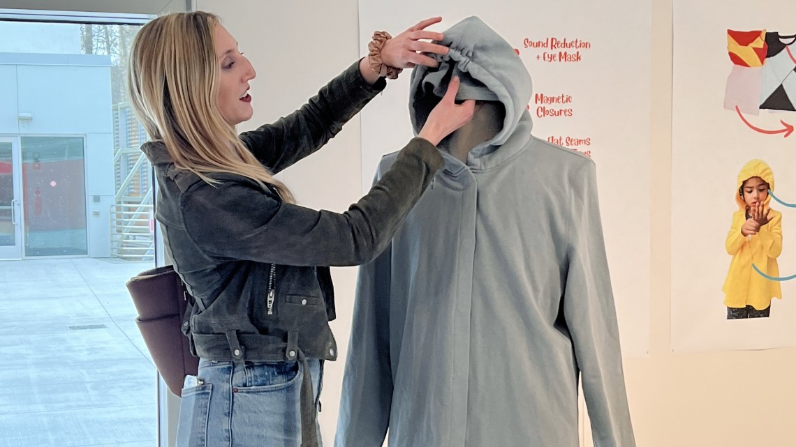 Julia DeNey ’20 demonstrates the hidden functions of a sweatshirt in the exhibit.
