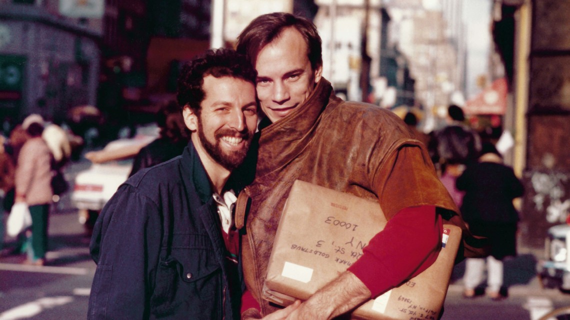 two men on the streets of New York City holding a package