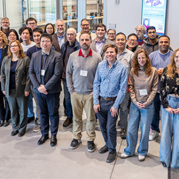 About 40 people stand outside of a classroom in an academic building