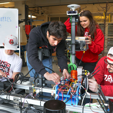 Andrew James ’26 (from left), Neil Morrison ’28, Natalia Kurz ’29 and Michael Neiss ’27 work on a prototype of their weed-killing robot ahead of The Farm Robotics Challenge, which they won on May 21.