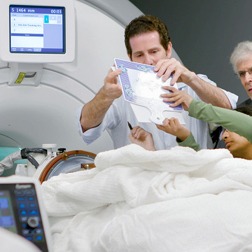 As colleagues looked on, neurosurgeon Dr. Michael Kaplitt (center) in 2016 assessed a patient’s dexterity during an MRI-guided treatment for a patient with essential tremor. The procedure is the same as that used to treat Stan Au’s Parkinson’s disease.