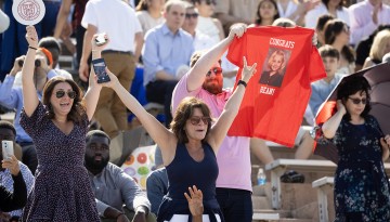 Family members cheer and hold up a t-shirt. 