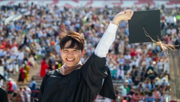 A graduate smiling, about to throw his cap. 