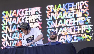 A ma with DJ equipment in front of a backdrop that says 'Snakehips".