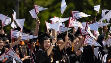 Graduates wave pennants.