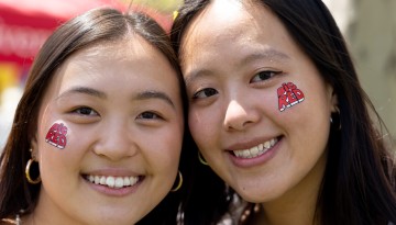 Two women with Big Red temporary tattoos on their faces. 