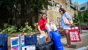 A new student and mother with belongings in front of residence hall on Move-in Day, 2015.