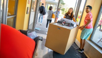 Students moving boxes into a residence hall. 