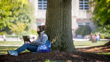 A student studies in the shade of the Ag Quad.