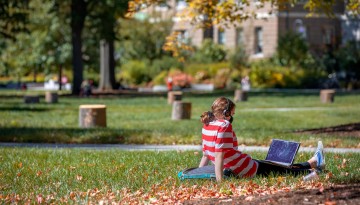 A student studies in the warm afternoon sun on the Ag Quad.