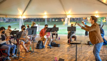 James Spinazzola lead students during rehearsal under a tent on the Arts Quad for his Music 3631 Wind Symphony class.