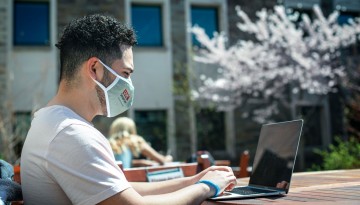 A student works in the courtyard of Ives Hall.