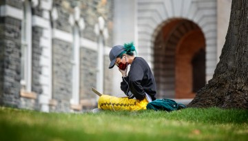 A student works in the grass outside Sibley Hall.