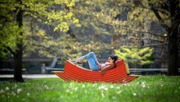 A student relaxes in the sun on the Artrs Quad.