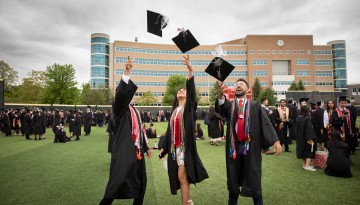 Three graduates throw their caps in the air. 