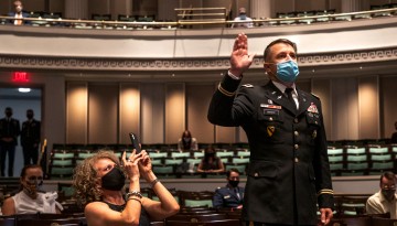 A man in uniform holding up his hand in oath. 