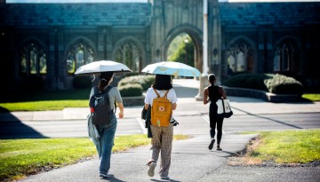 Umbrellas shade students from the sun as they walk toward West Campus.