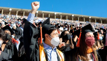 A graduate holds up a fist in celebraton. 