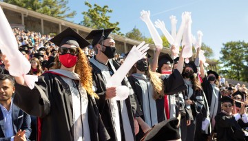 Graduates of the Vet College wave blown-up rubber gloves. 
