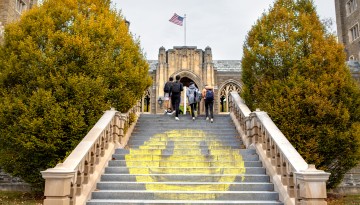 Students walk past a giant smiley face chalk art on West Campus.