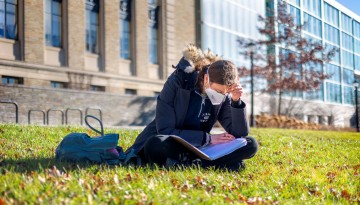 A student takes advantage of a warm December afternoon to study outside.