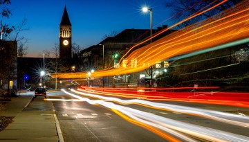 McGraw Tower is seen at night as cars and busses pass by on Tower Road in a long exposure photograph.