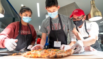 Members of the Meinig Family Cornell National Scholars Mentor Group slice a pizza they made in Morrison Dining Hall.