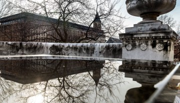 A wet marble surface near Goldwin Smith Hall reflects a scene on the Arts Quad.
