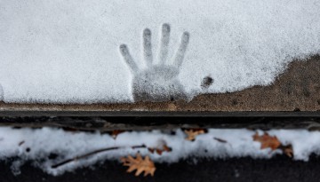 A hand impression in the snow slowly melts away near the Arts Quad.