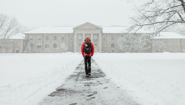 A student walks through a snowy Arts Quad in January.