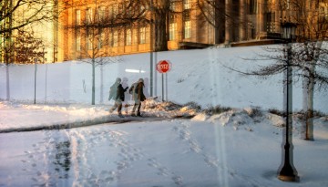 Students walk by a snowy Milstein Hall in the evening.
