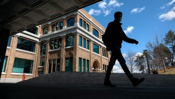 A student passes by Rand Hall on a clear spring day.