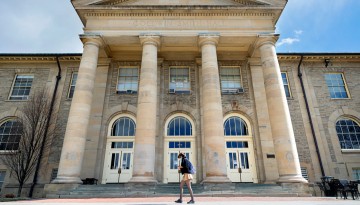 A student walks to class in front of Goldwin Smith Hall.