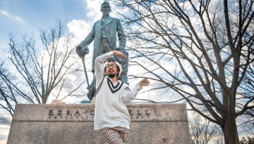 A student dances in front of the Ezra Cornell statue on the Arts Quad.
