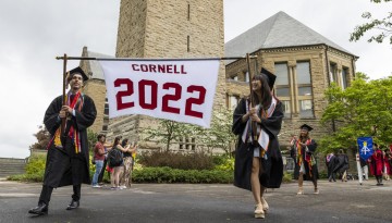 Two graduates holding a Cornell 2022 banner.