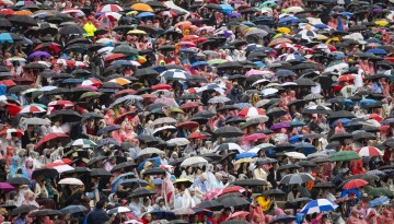 A crowd of spectators holding umbrellas. 