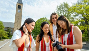 Students look at graduation photos by McGraw Tower.