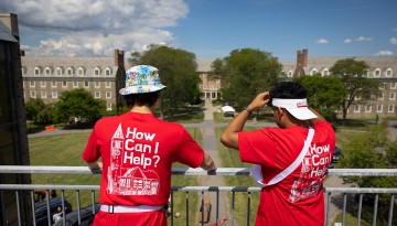 Two student volunteers look out over the railing towards the residence halls. 