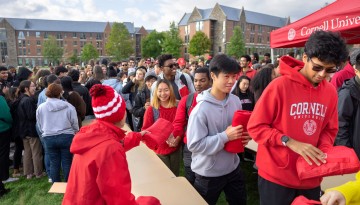 Members of the Class of 2026 pick up Cornell blankets during a class photo on Rawlings Green.