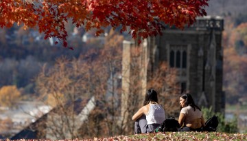 Students sit atop Libe Slope on an autumn day.
