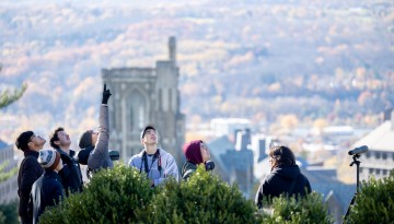 Students look for birds on Libe Slope on an autumn day.